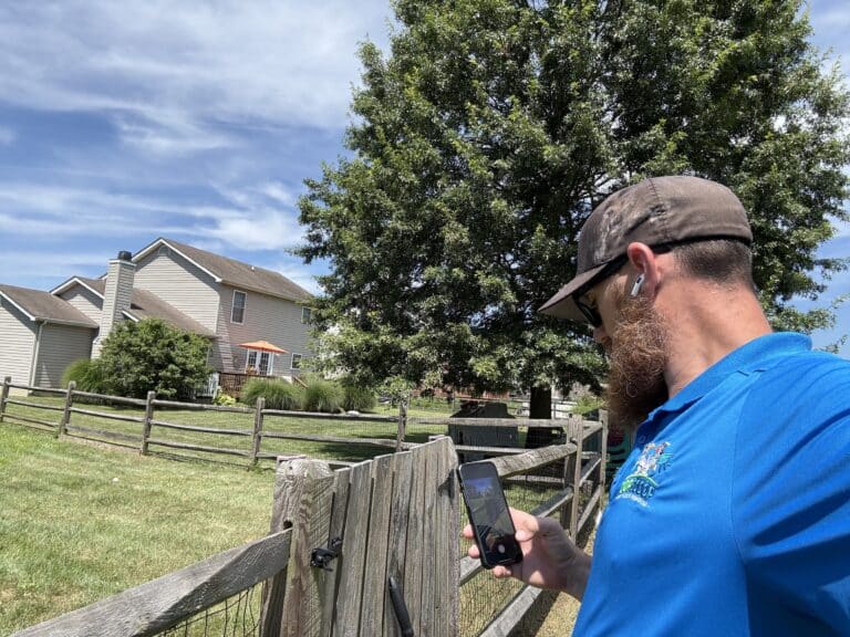 Oop Scoop technician taking a locked gate photo to confirm secure service for pet waste removal in Delaware and Maryland.