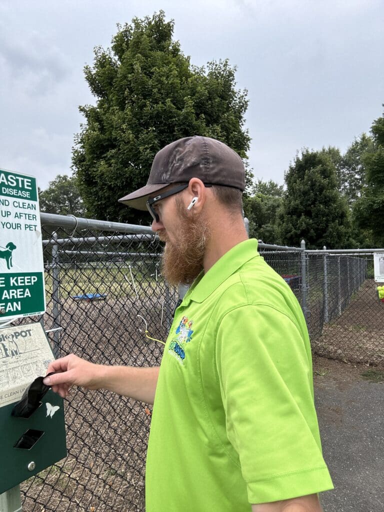 Oop Scoop technician servicing a dog waste station, representing commercial pet waste removal and dog waste management services in Delaware and Maryland.